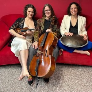 three women sit on a couch holding musical instrucments