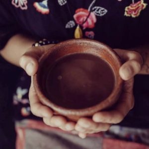 hand hold a ceramic cup of cacao