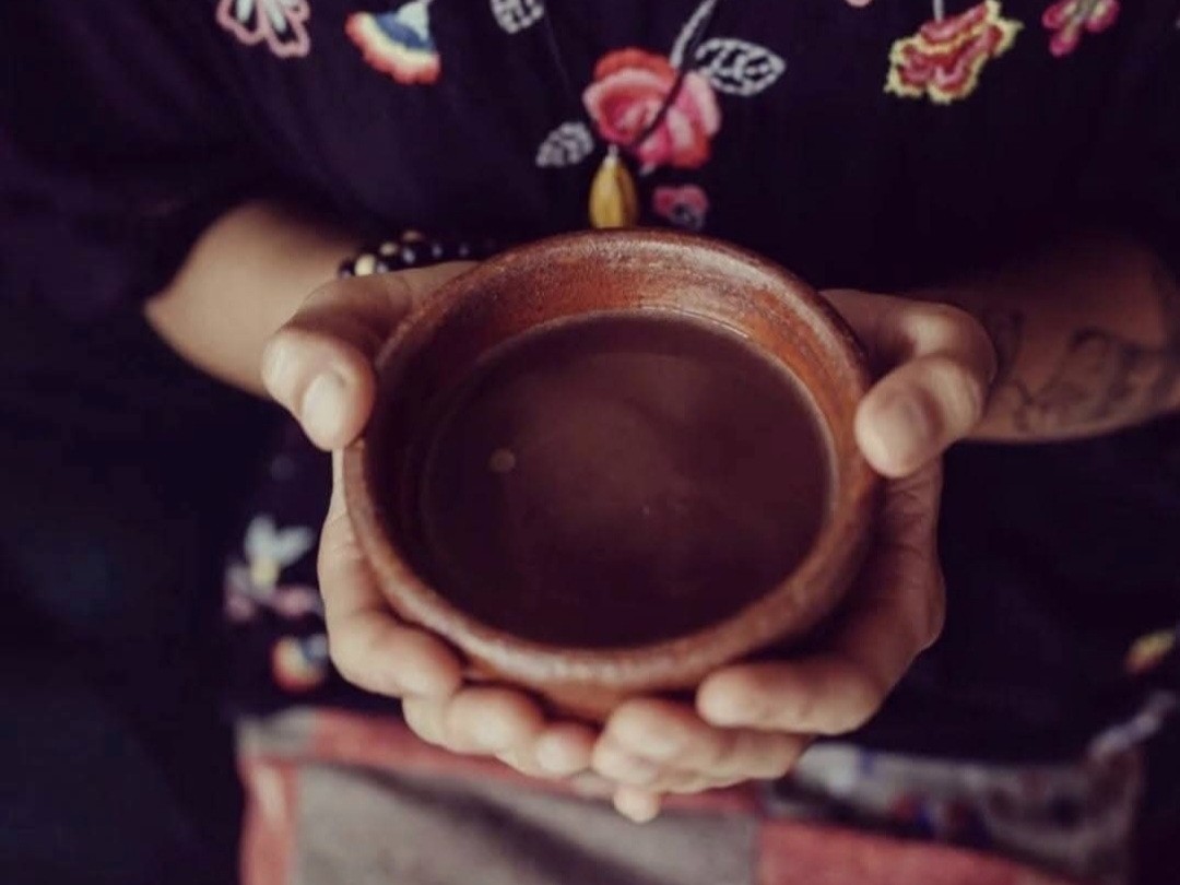 hand hold a ceramic cup of cacao